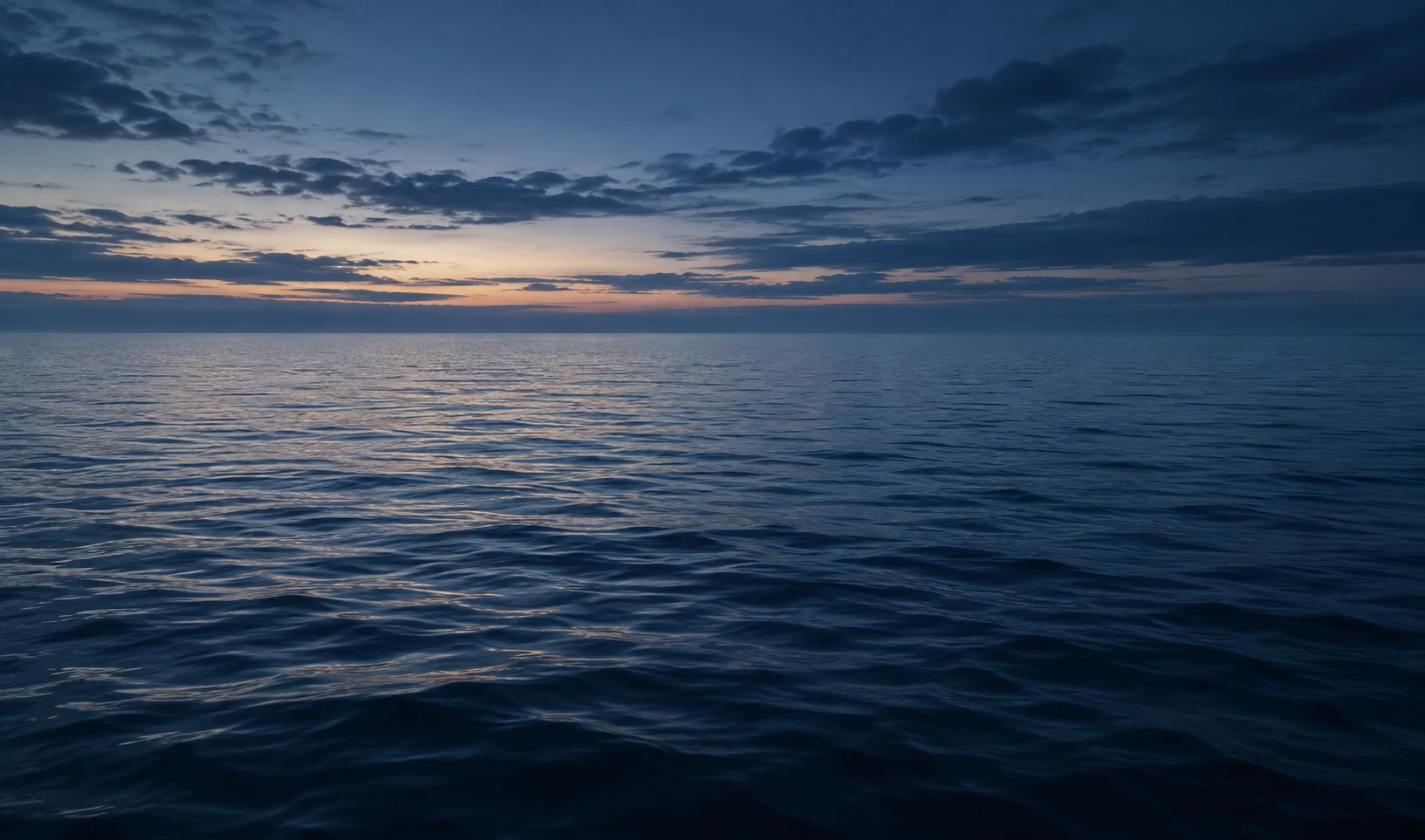 Calm open ocean beneath a blue twilight sky